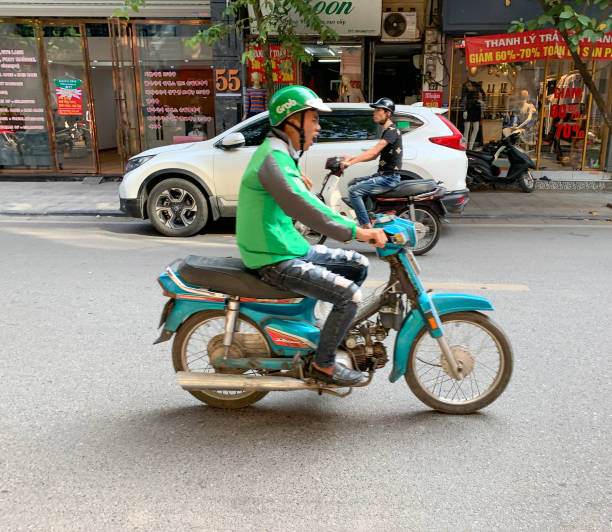 Asian man Grab driver Hanoi, Vietnam - November 15,2019 : Asian man Grab worker rides motor scooter while yawning. vietnamese man taxi motorbike driver stock pictures, royalty-free photos & images