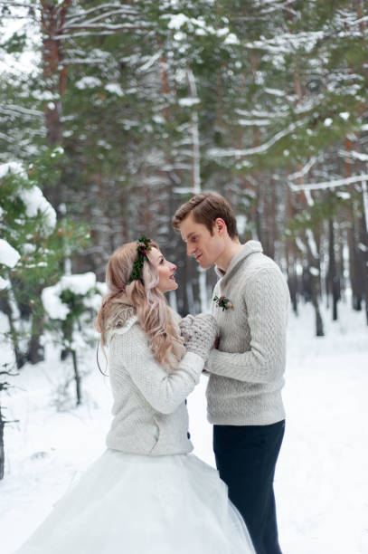 istock Bride and groom in beige knitted pullovers in snowy forest. Newlyweds is touching foreheads. Winter wedding. Copy space 1218903680