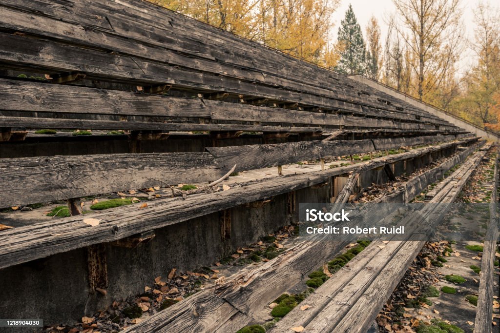 Detail of broken wooden seat benches on grandstand of abandoned sports arena in Pripyat, Chernobyl Exclusion Zone in autumn Abandoned Stock Photo