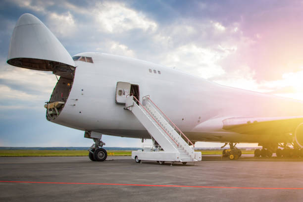 rozładunek widebody samolot towarowy w fartuchu lotniska w słońcu rano. spędła kabina z łukiem samolotu towarowego otwarta. wejście na pokład samolotu - luggage ramp zdjęcia i obrazy z banku zdjęć