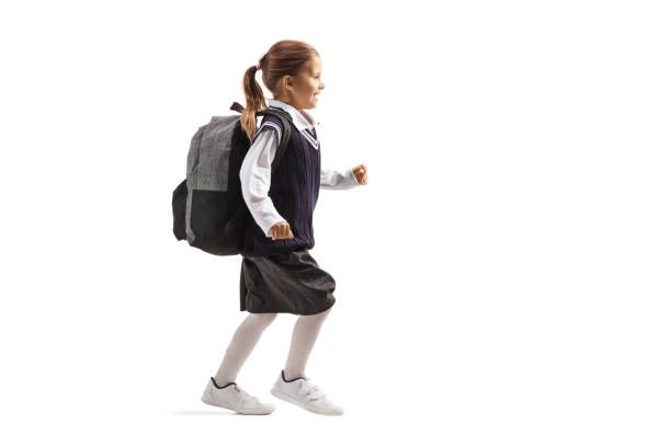 istock Schoolgirl in a uniform with a backpack running 1218911690