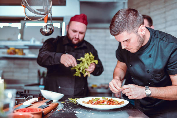 Devoted Male Cooks Making Good Food In Modern Restaurant Kitchen