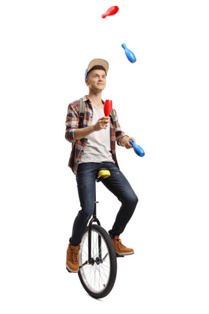 jonge mannelijke student die op een eenwieler jongleert - jongleren stockfoto's en -beelden
