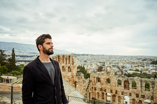 Cropped shot of a handsome young man standing alone near the Odeon of Herodes Atticus while sight-seeing in Greece
