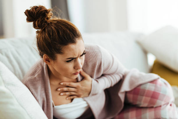 istock Young woman feeling chest pain while lying down on sofa at home. 1218916725