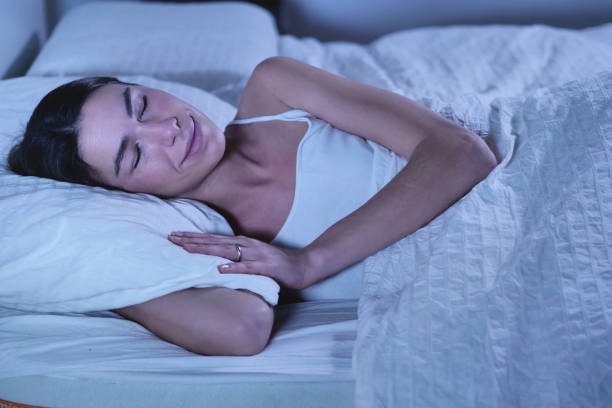 istock A beautiful young girl sleeping in a warm bed, covered with a soft  warm white blanket, on a white background. 1218919893