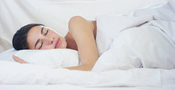 istock A beautiful young girl sleeping in a warm bed, covered with a soft  warm white blanket, on a white background. 1218919934