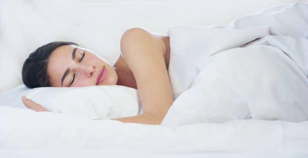 istock A beautiful young girl sleeping in a warm bed, covered with a soft  warm white blanket, on a white background. 1218920003