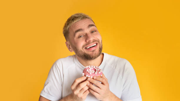 istock Sweet tooth man happy eat donut, panorama 1218926112