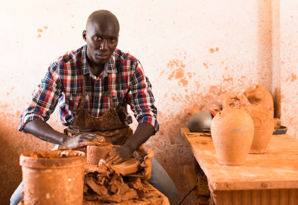 Man making ceramics on pottery wheel Portrait of positive afro man making ceramic pot on pottery wheel hobbyist stock pictures, royalty-free photos & images
