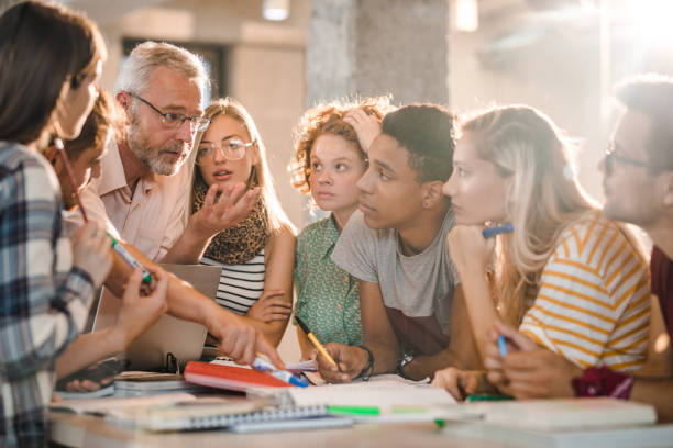 istock Mature teacher teaching group of college students at campus. 1218926399