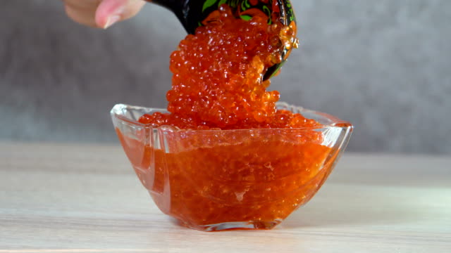 Close-up. Spoon put caviar in a glass vase