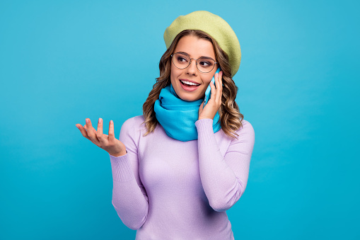 Portraut of cheerful girl call smartphone, have conversation with her friend tell recent fall weekend winter news wear headwear trendy jumper isolated over blue color background