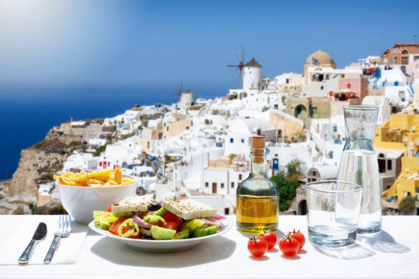 griechische küche mit salat, bratkartoffeln und frischem olivenöl vor dem dorf oia in santorni, griechenland - olive oil salad mediterranean cuisine olive stock-fotos und bilder