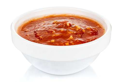 Hot tomato sauce with spices and salt in a small white ceramic round bowl isolated on white background