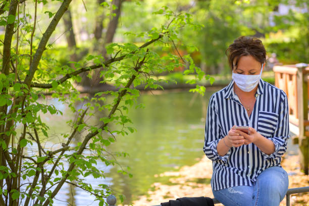 istock Woman relaxing with a mobile phone in a park 1218933225