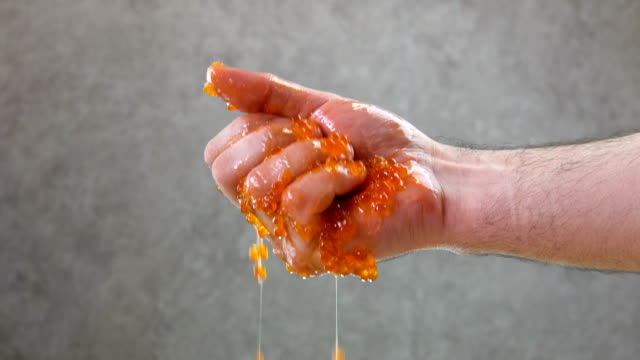 Male hand squeezes red caviar