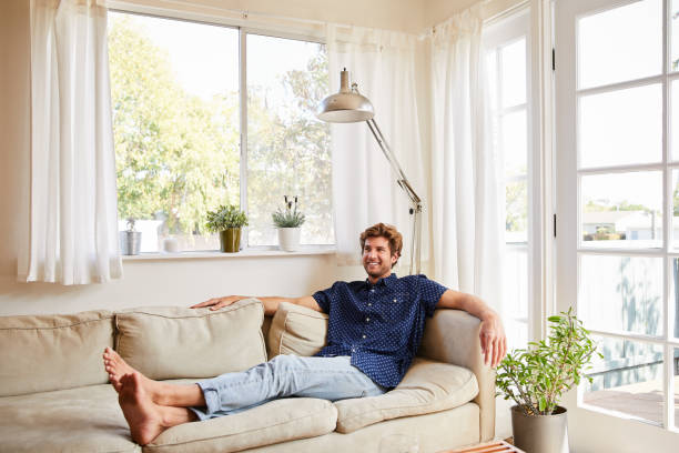 istock Smiling young man lying on his living room sofa 1218934808