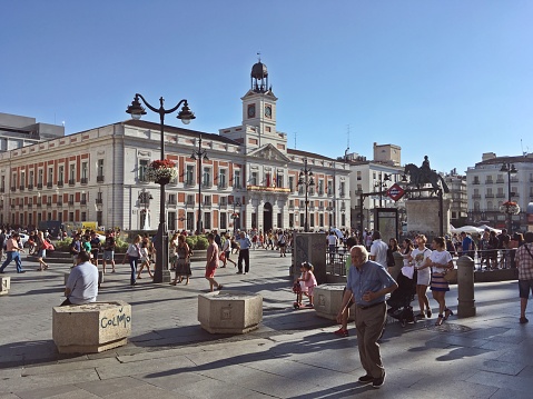 Madrid/Spain; 07/23/2018. Tourists and locals, strolling on a sunny summer day. The Royal Post Office at the background.
