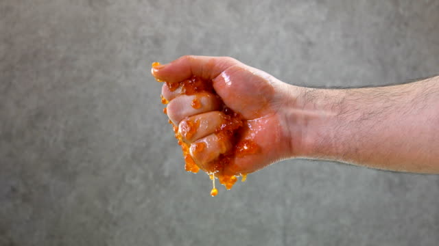 Male hand squeezes red caviar. Close-up