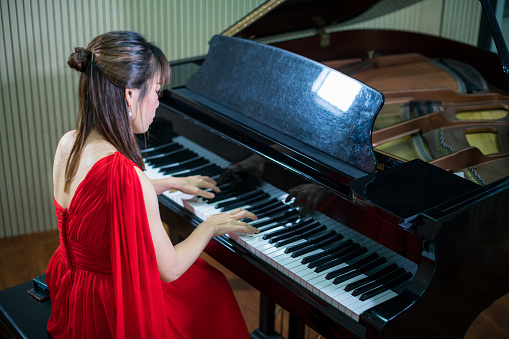 The beautiful young Asian girl is playing the piano