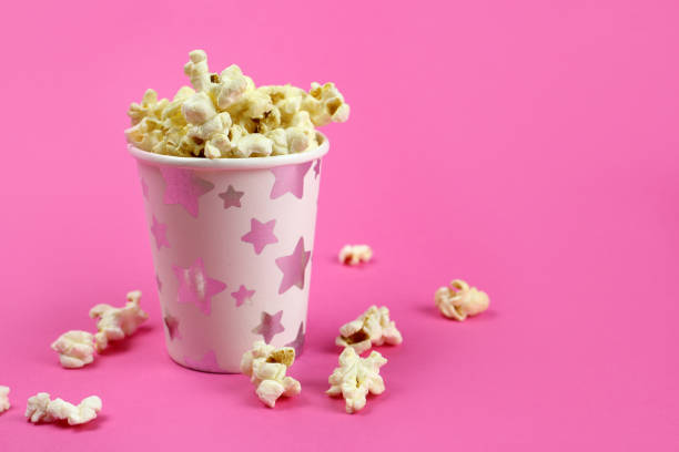istock caramel popcorn in a paper Cup on a pink background, copy space 1218940468