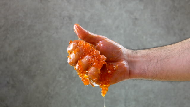 Male hand tightly squeezes red caviar