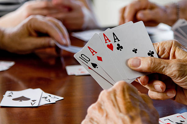 istock Friends sitting around a table playing cards with each other 121894547