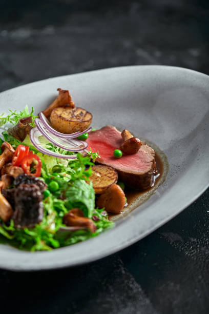 istock beef tagliata with vegetables. Close-up, low key, gray background 1218945569