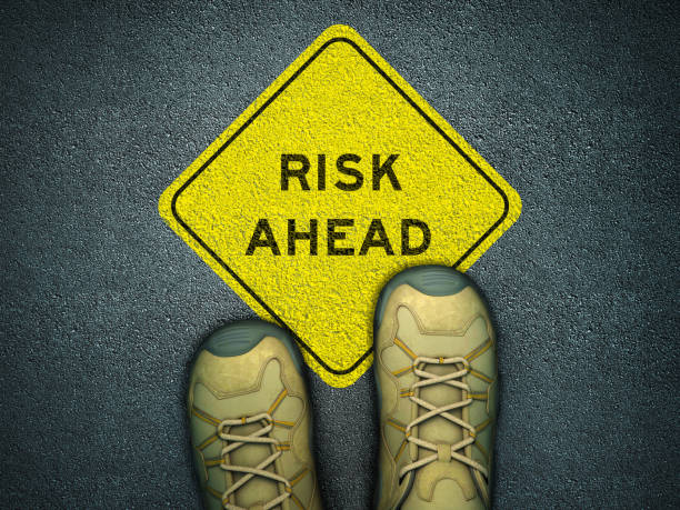 istock Feet on Asphalt Road with RISK AHEAD Road Sign - 3D Rendering 1218946823