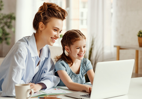Chica feliz con la madre estudiando en línea en casa photo