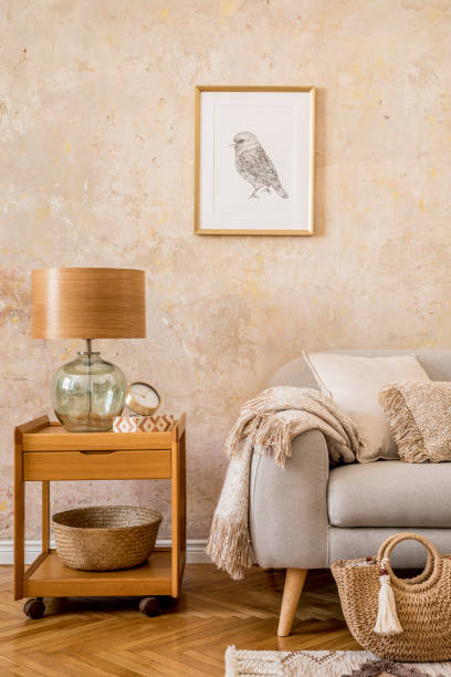 Stylish scandi compostion at living room interior with design gray sofa, furniture, decoration, plants and elegant accessories in home decor. concepto elegante de interior de la sala de estar con mesa de centro, lámpara de mesa, sofá gris de diseño, marco de imagen de maqueta, libros, alfombra, bolsa de mujer, almohada, a cuadros y accesorios elegantes en la decoración del hogar.