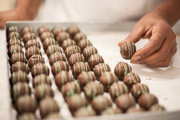 Preparing sweet candies Close-up shot of a woman chocolatier making chocolate sweets at confectionery shop chocolate truffle making stock pictures, royalty-free photos & images
