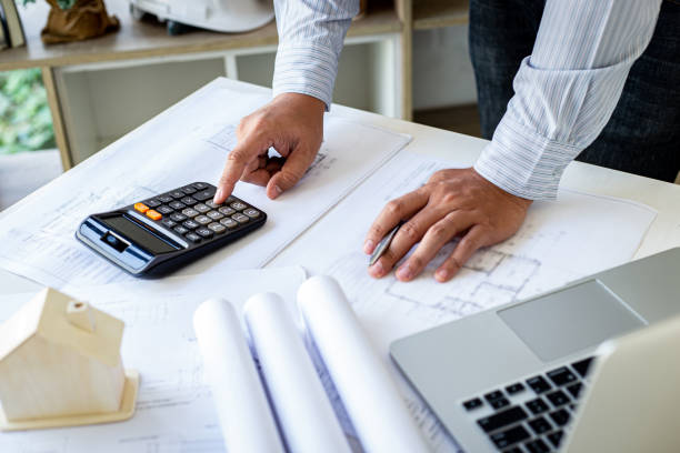 istock The engineer designed the house structure in the blueprint and working in the architect's room, There are equipment for designing laptops, pens, pencils, drawings And sample house with mold 1218955068