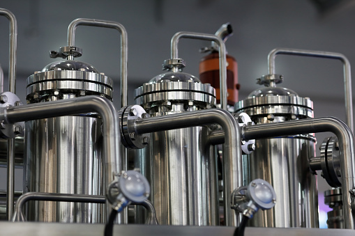 Stainless steel tanks, pipes, and fittings. Closeup view of the system for producing water for injection WFI. Selective focus.