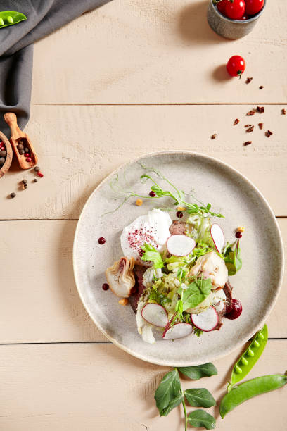 istock Roast beef, artichokes and poached egg salad in white plate top view 1218959597