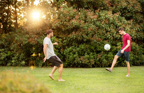 Playing a quick game of soccer Shot of two young male friends playing football in the garden soccer soccer ball kicking adult stock pictures, royalty-free photos & images