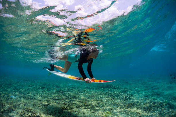 istock Girl dives under the wave with surfboard 1218961191