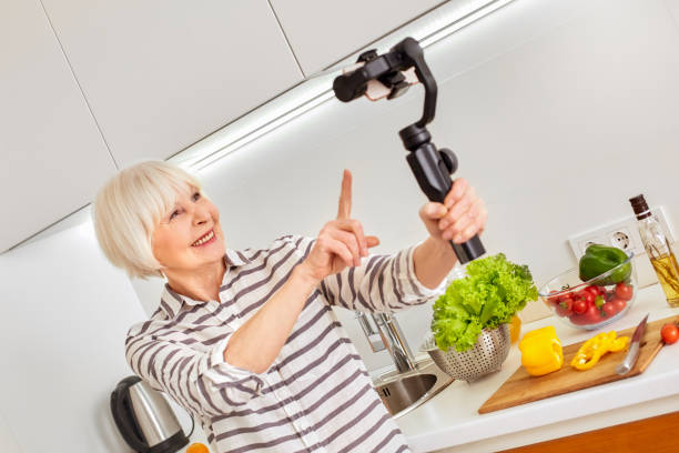 istock Modern selfie video record phone camera. New technology online program. Indoor home hobby food blog blogger. Social active old woman followers advertise maker. Healthy meal podcast posting preparing. 1218961301