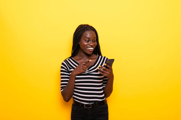 istock Young african american woman using smartphone standing over isolated yellow background 1218963156