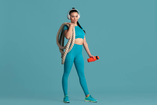istock Beautiful young female athlete practicing on blue studio background, monochrome portrait 1218966745