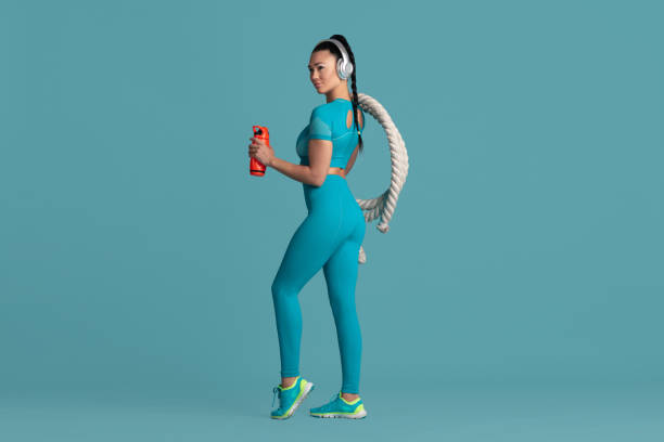 istock Beautiful young female athlete practicing on blue studio background, monochrome portrait 1218966752
