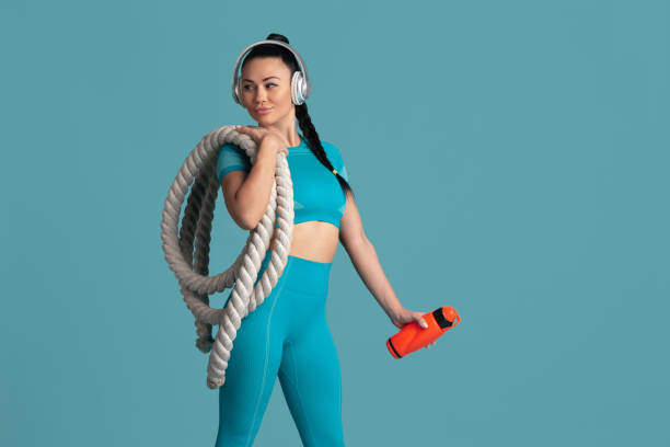 istock Beautiful young female athlete practicing on blue studio background, monochrome portrait 1218966755