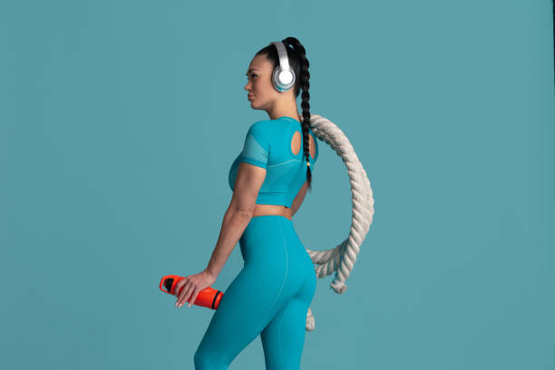 istock Beautiful young female athlete practicing on blue studio background, monochrome portrait 1218966774