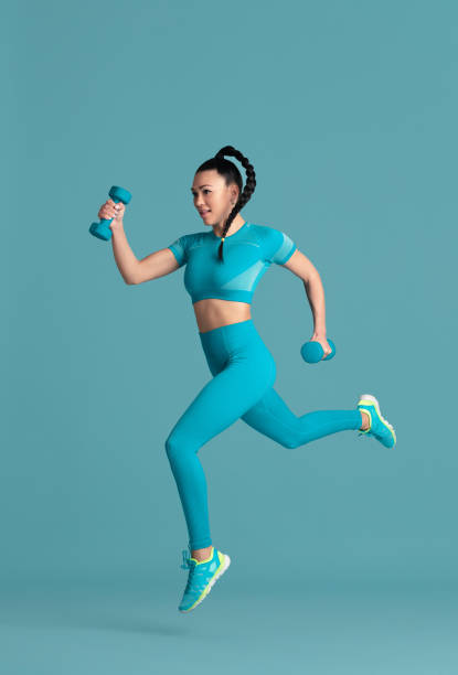 istock Beautiful young female athlete practicing on blue studio background, monochrome portrait 1218966775
