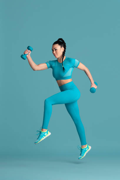 istock Beautiful young female athlete practicing on blue studio background, monochrome portrait 1218966787