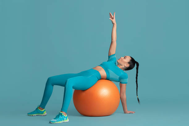 istock Beautiful young female athlete practicing on blue studio background, monochrome portrait 1218966819