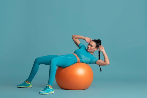 Beautiful young female athlete practicing on blue studio background, monochrome portrait