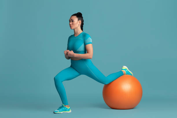 istock Beautiful young female athlete practicing on blue studio background, monochrome portrait 1218966866