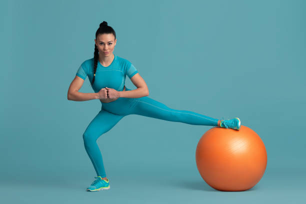 istock Beautiful young female athlete practicing on blue studio background, monochrome portrait 1218966869